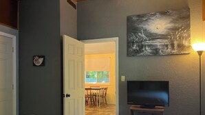Ein Schlafzimmer mit Bett, Fernseher, einem Bild und einer Tür zum Essbereich.
