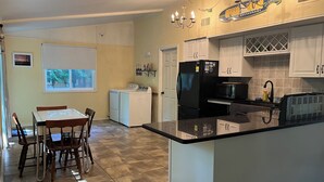 Eine moderne Küche mit Kochinsel, Essbereich mit Tisch und Stühlen sowie Waschküche mit Waschmaschine und Trockner.