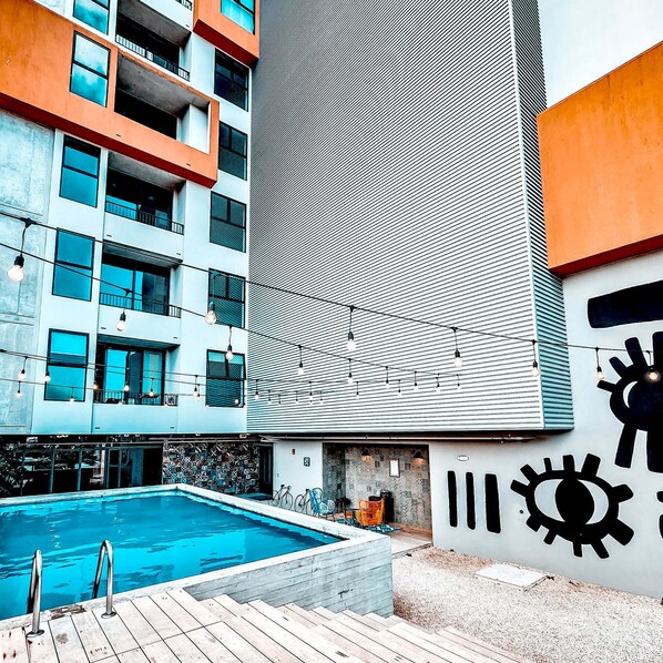 A modern building with a pool, outdoor seating, and a large wall with a geometric pattern.