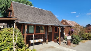 A rustic wooden building with a sloped roof, a bench outside, and a signboard. - Cozy Country Cottage in the heart of Skagit Valley! (Mount Vernon)