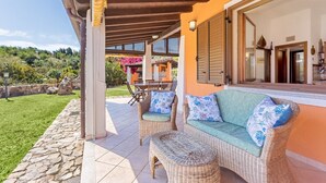 A covered patio with wicker furniture, a stone pathway, and a view of a hillside. - Terraced house with swimming pool (Tertenia)