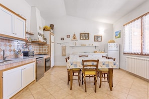 A kitchen with a dining table, chairs, and various kitchen appliances.