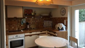 Eine Küche mit rundem Tisch, Backofen und einer Uhr an der Wand.