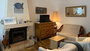 Ein Wohnzimmer mit Kamin, Fernseher, Lampe und Spiegel.