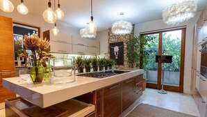 Una cocina moderna con una isla grande, luces colgantes y una pared de acento de piedra.