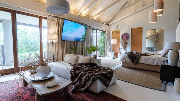 Un salón amplio con televisor grande, asientos cómodos y vistas a zonas verdes.
