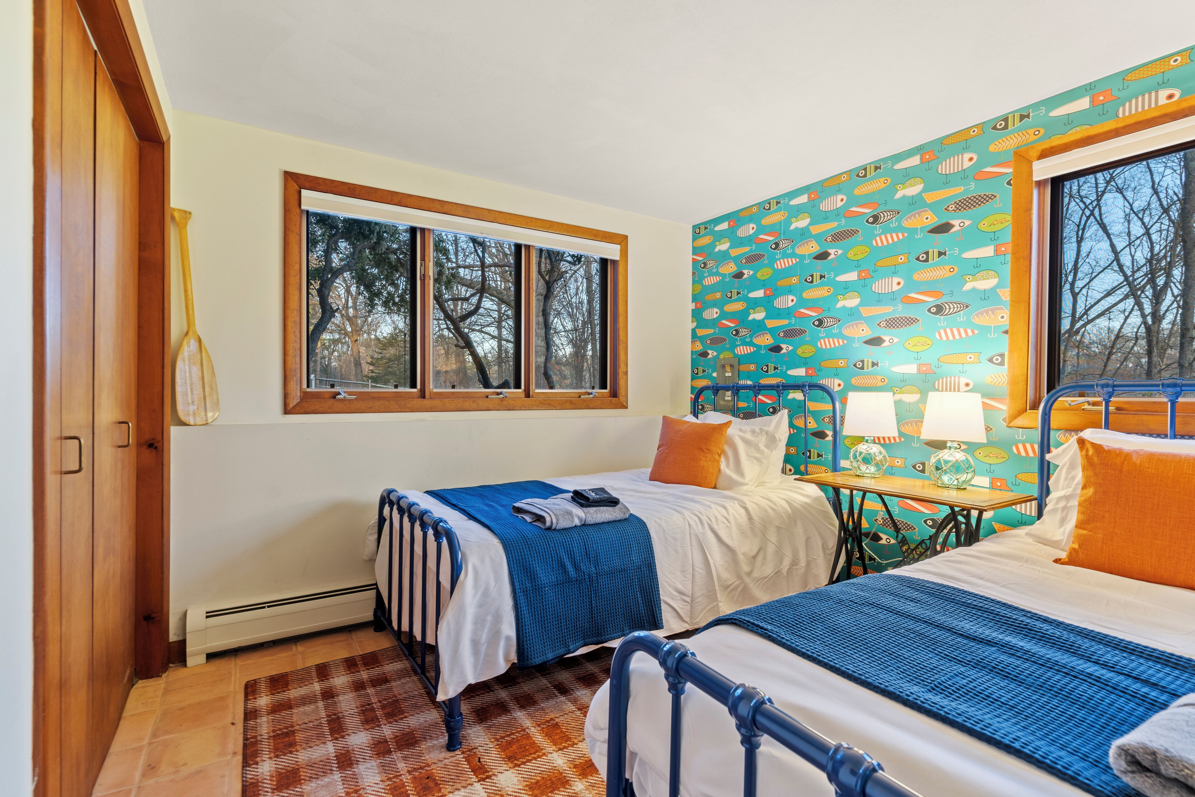 Quarto com duas camas, janela, radiador e parede estampada.