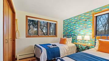 Quarto com duas camas, janela, radiador e parede estampada.