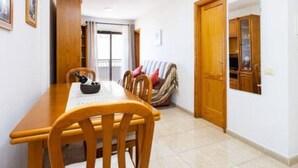 A dining area with a wooden table and chairs, a small rug, and a door leading to another room.
