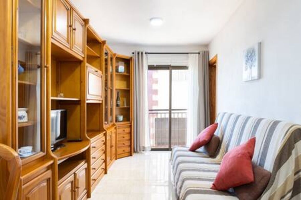 Una sala de estar con un sofá, armarios de madera y un televisor.