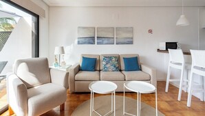 Ett modernt vardagsrum med en soffa, två sidobord, ett soffbord och en matplats med stolar.