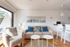 A modern living room with a sofa, two side tables, a coffee table, and a dining area with chairs. - Home2Book Design Apt Pool & Terrace Golf del Sur (San Miguel de Abona)