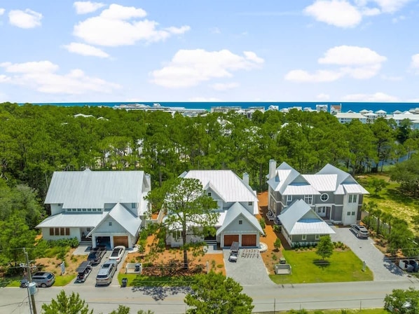 A residential area with multiple houses, a parking area, and a view of the ocean.