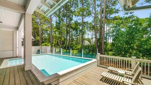 A wooden deck with a swimming pool, surrounded by trees.