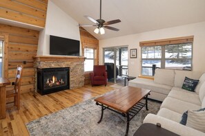 A living room with a fireplace, wooden walls, a sofa, a coffee table, and a television.