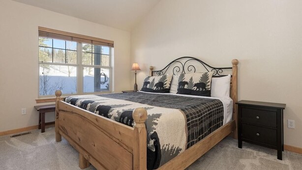 A bedroom with a wooden bed, a nightstand, a bench, and a window with blinds. - 40 Reunion Ct w/ private hot tub (Fraser)