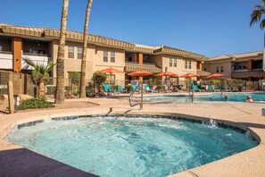 A hotel with a swimming pool, lounge chairs, and palm trees.