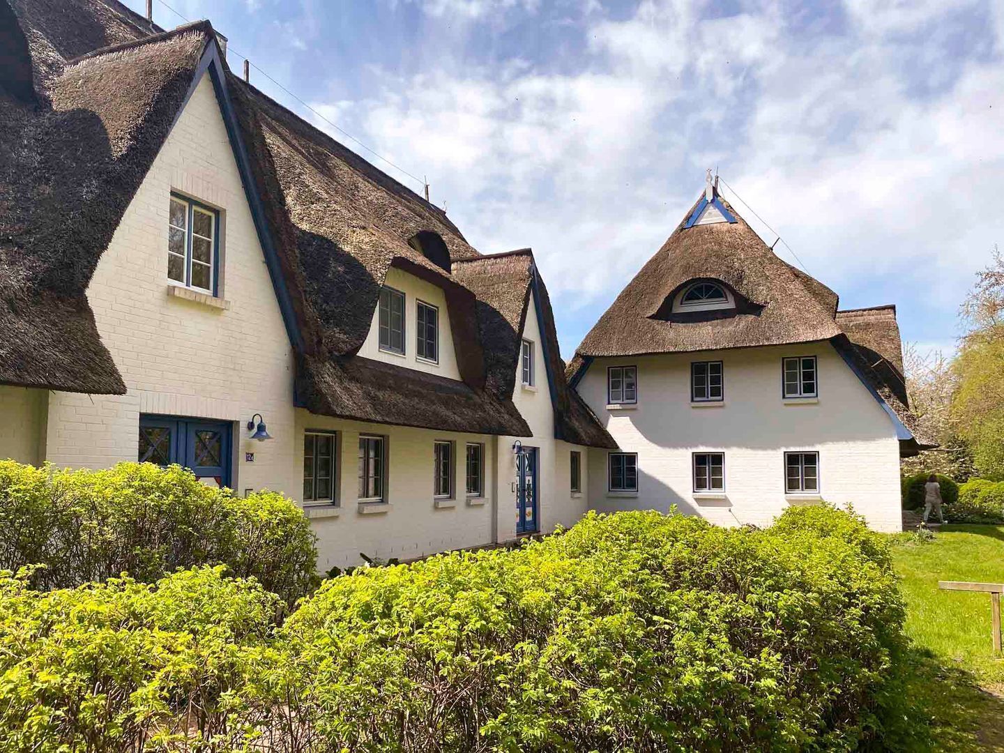 A traditional building with a steeply pitched roof, multiple windows, and a well-maintained garden.