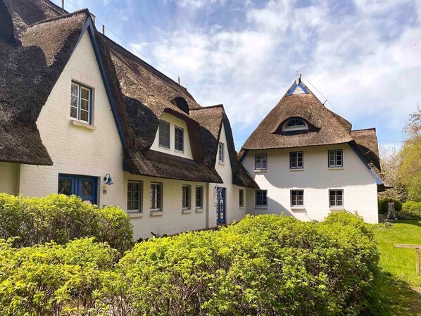 A traditional building with a steeply pitched roof, multiple windows, and a well-maintained garden. - Gemütliche Ferienwohnung in Reetgedeckter, Ruhiger Ferienanlage! - Achtern Diek (Zingst)