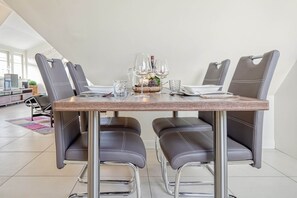 A dining table with four chairs, a glass of water, a glass of wine, and a candle on the table. - Helle, Freundliche Ferienwohnung in Strandnähe! - Kavelweg 9 (Zingst)