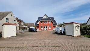 A residential area with a red house, a driveway, and parked cars. - Helle, Freundliche Ferienwohnung in Strandnähe! - Kavelweg 9 (Zingst)