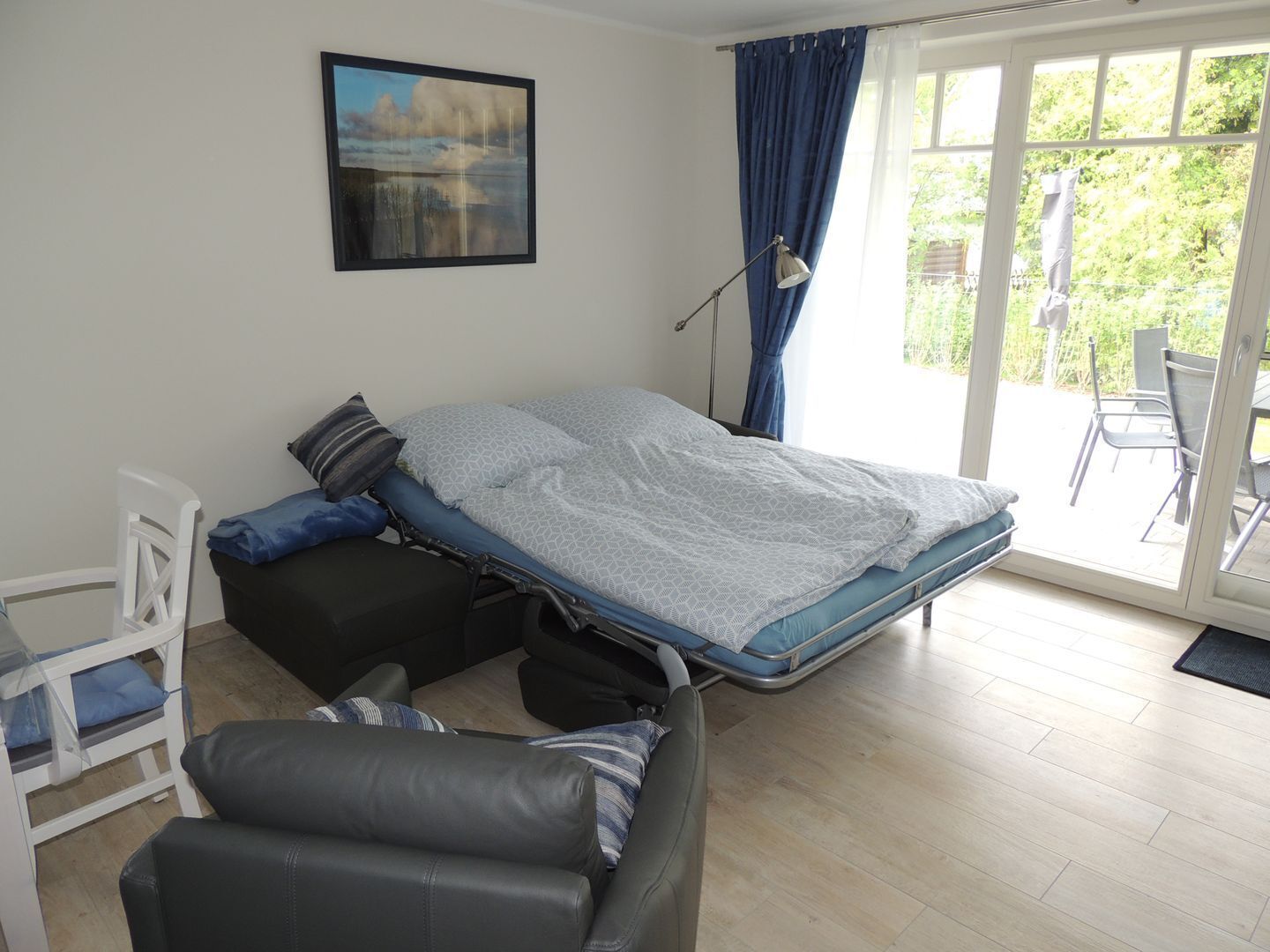 Un dormitorio con cama, una silla, un escritorio y vistas al exterior.