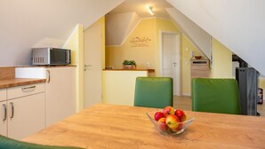 A compact kitchen with a microwave, a wooden countertop, and a bowl of fruit on a table. - Helle, Freundliche Ferienwohnung in Strandnähe! - Kavelweg 13 (Zingst)