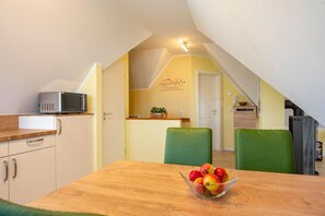 A compact kitchen with a microwave, a wooden countertop, and a bowl of fruit on a table. - Helle, Freundliche Ferienwohnung in Strandnähe! - Kavelweg 13 (Zingst)