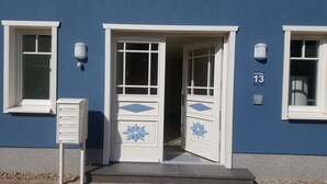 A building with a blue exterior, white doors, and a mailbox. - Helle, Freundliche Ferienwohnung in Strandnähe! - Kavelweg 13 (Zingst)