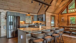 A spacious kitchen with a large island, bar stools, and a dining area with a wooden table and chairs.