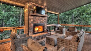 A cozy outdoor seating area with wicker furniture and a stone fireplace.