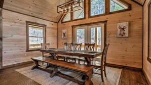 A wooden interior with a large dining table, benches, and framed animal pictures on the walls.