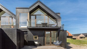 A modern two-story house with a balcony, large windows, and a wooden exterior. - Ocean front home in Skagen with WiFi (Skagen)