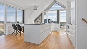 A modern kitchen with large windows, a dining area with chairs, and a view of the outdoors. - Ocean front home in Skagen with WiFi (Skagen)