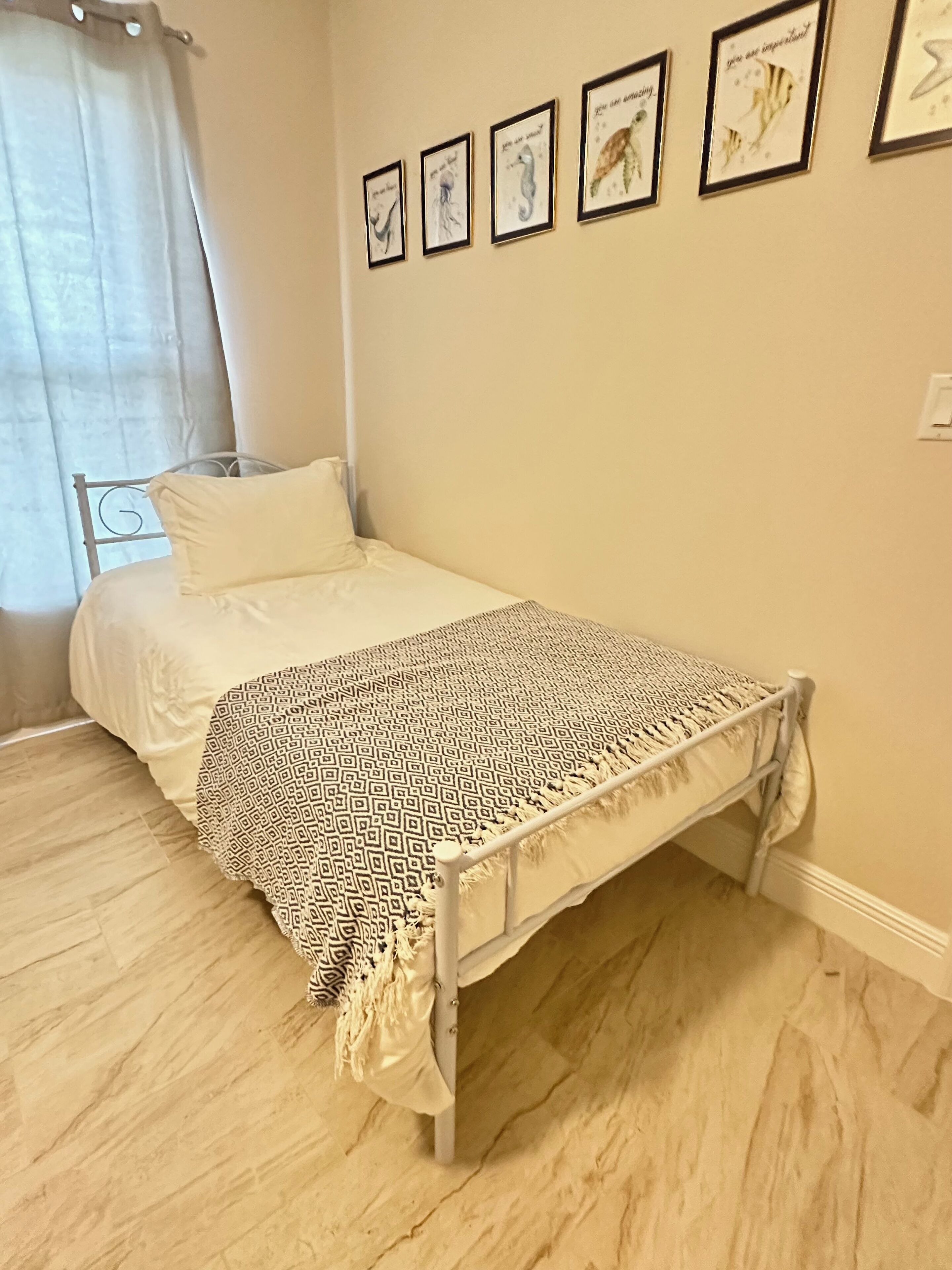 Ein Schlafzimmer mit einem Bett, einer gemusterten Tagesdecke und vier gerahmten Wandbildern.