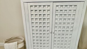 A white cabinet with a woven basket and a tissue box on top.