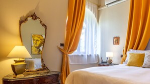 A hotel room with a bed, a dresser, a lamp, a mirror, and curtains. - Villa Magnolia - Apartment in villa (Giardini Naxos)