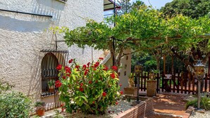 A courtyard with a white building, a pergola with climbing plants, and a brick pathway. - Villa Magnolia - Apartment in villa (Giardini Naxos)