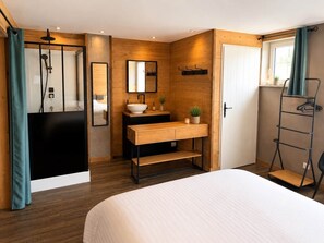 Een moderne badkamer met een houten wastafelmeubel, een grote spiegel en een douchehoek.