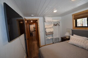 Ein Schlafzimmer mit einem Bett, einem Kleiderschrank, einem Nachttisch mit Lampe und einem Fenster mit Blick nach draußen.