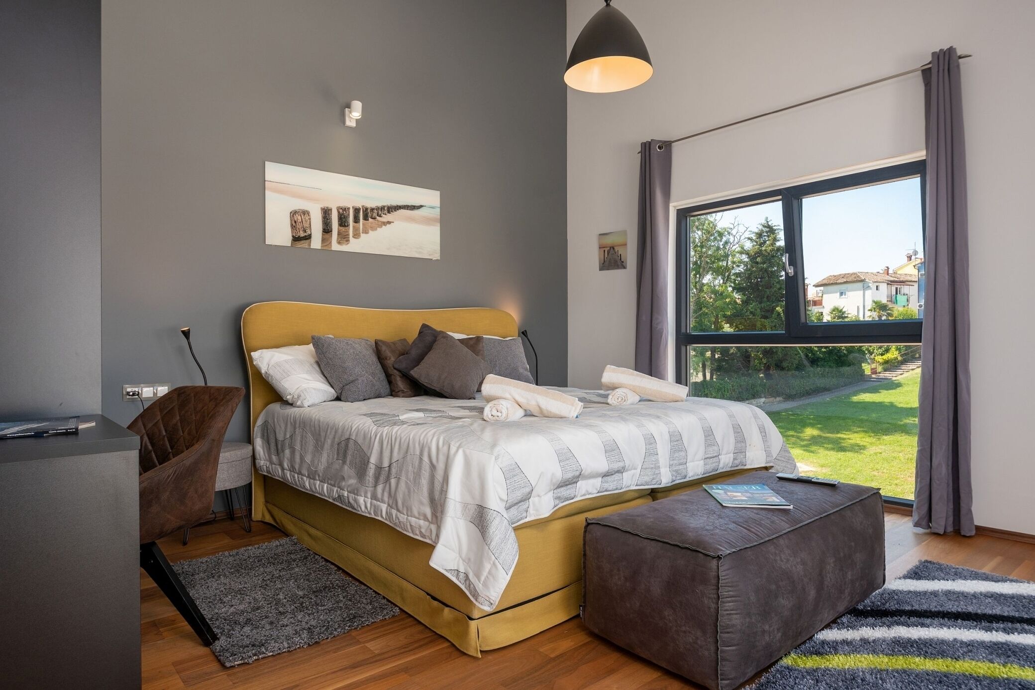 A modern bedroom with a bed, bedside table, and a large window.