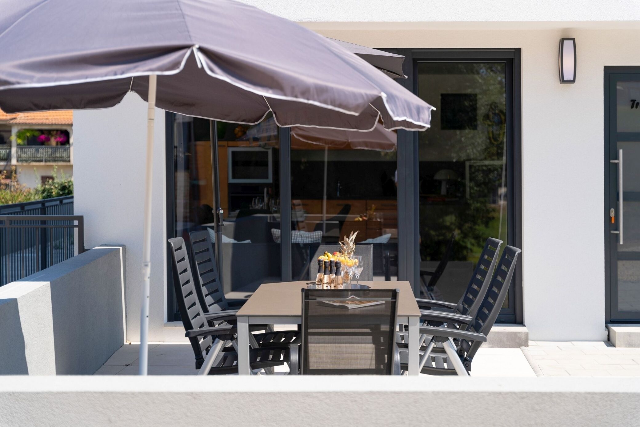 An outdoor patio with a table and chairs, an umbrella, and a glass door leading to an interior space.