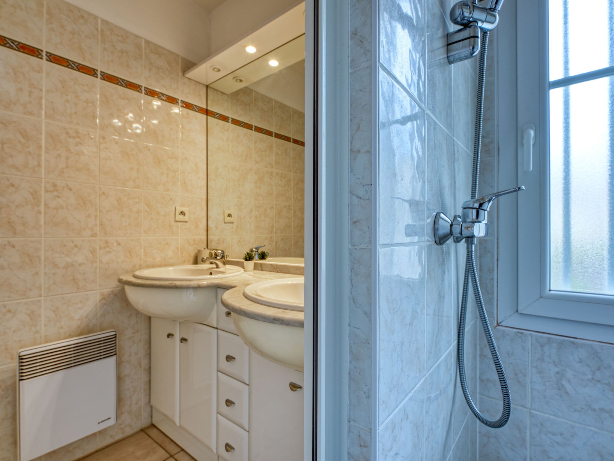 A modern bathroom with two sinks, a shower, and a radiator.