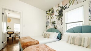 Hotellihuone, jossa on kaksi sänkyä, työpöytä ja tuoli.