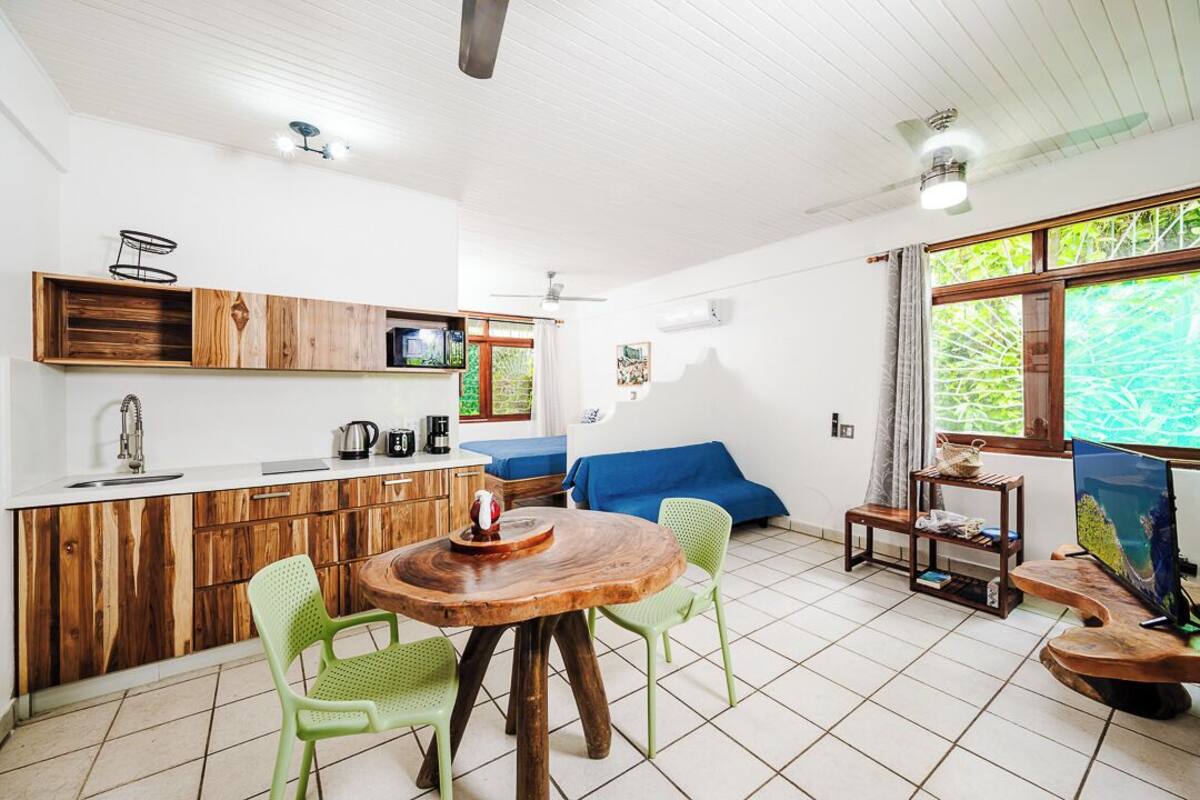 A compact living space with a kitchenette, dining area, and a large window with a view.