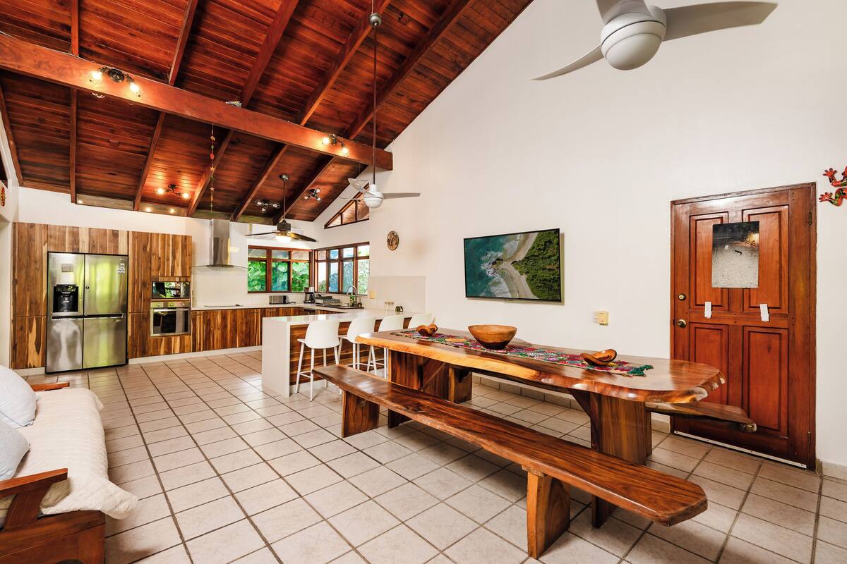 A spacious kitchen with wooden cabinets, a large island, and a dining area with a wooden bench and chairs.