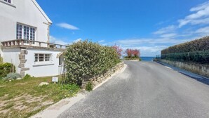 A coastal road with a white building on the left, a stone wall, and a hedge. - 2 bedroom cozy apartment in Saint-Pierre-Quiberon (Saint-Pierre-Quiberon)