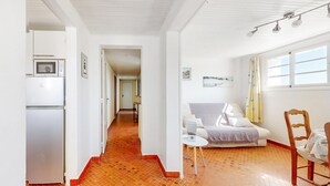 A bright, spacious room with a tiled floor, a bed, a small table, and a chair. A refrigerator is visible in the corner. - 2 bedroom cozy apartment in Saint-Pierre-Quiberon (Saint-Pierre-Quiberon)