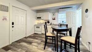 A compact kitchen with white cabinets, a microwave, an oven, and a dining area with a table and chairs. - 1 Bed Altamonte Springs Apartment Unit #2 (Altamonte Springs)
