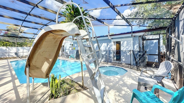 A covered outdoor swimming pool with a slide, lounge chairs, and a small garden area. - 1 Bed Altamonte Springs Apartment Unit #2 (Altamonte Springs)